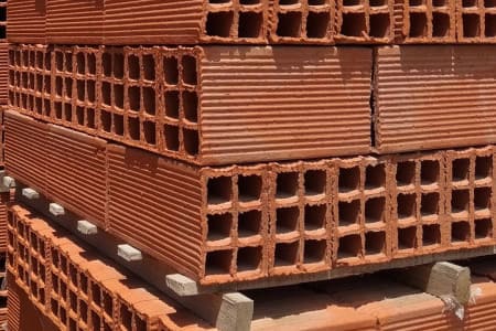 Pallets de ladrillo hueco apilados en el patio del corralón